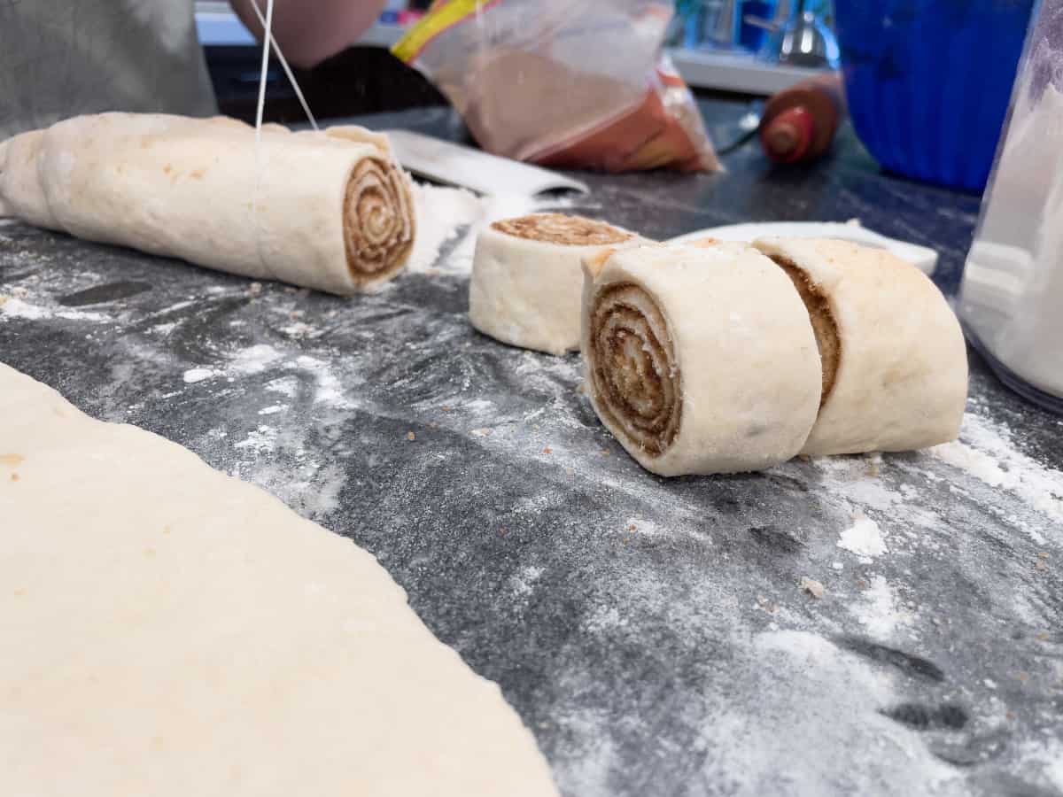 Cinnamon rolls being cut using dental floss