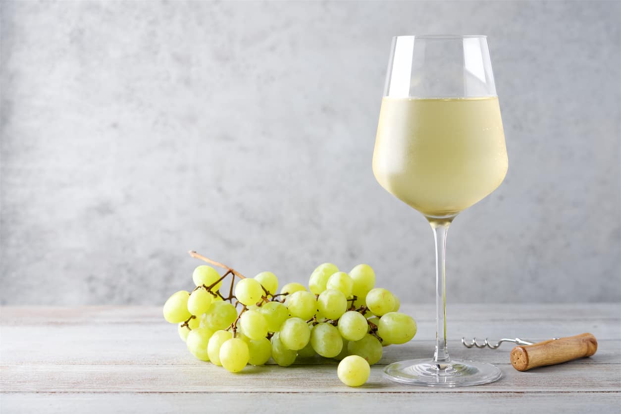 Sauvignon blanc in a glass next to a bunch of green grapes