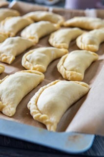 A sheet tray of pasties waiting to be baked.